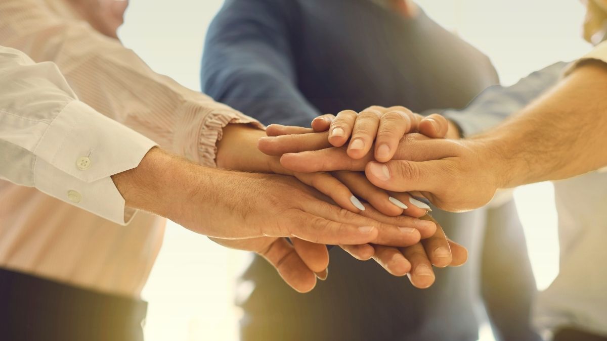 Hände eines Teams, die zur Teamarbeit zusammengeführt werden.